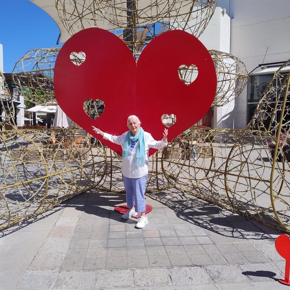 Paciente con los brazos abiertos frente a un gran corazón rojo