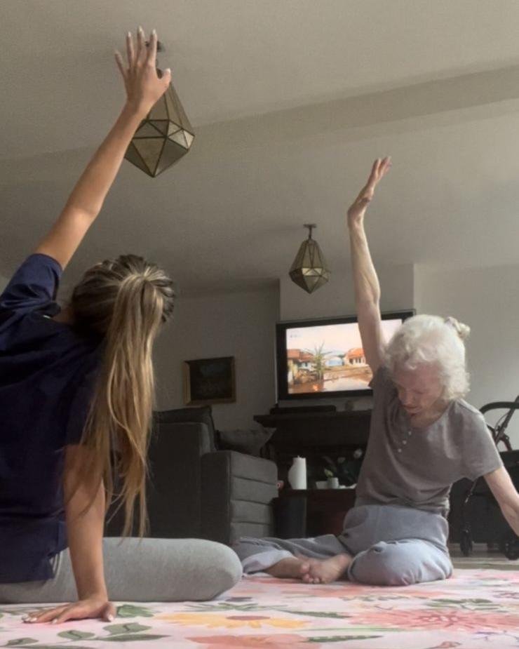 Paciente y cuidadora haciendo ejercicios de estiramiento en casa